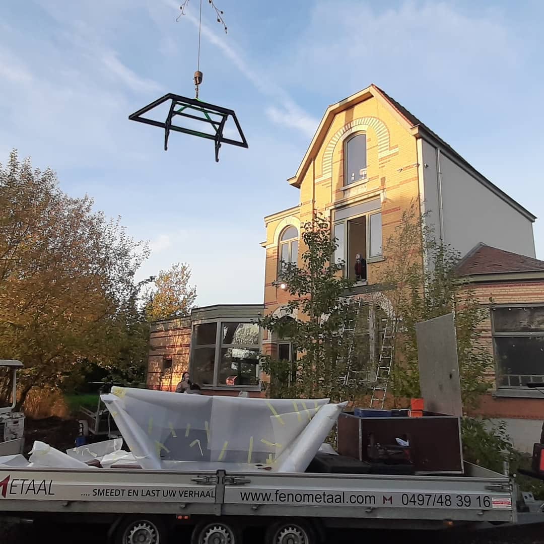 Smeedijzeren balkon dat met een kraan geplaatst wordt bij een herenhuis