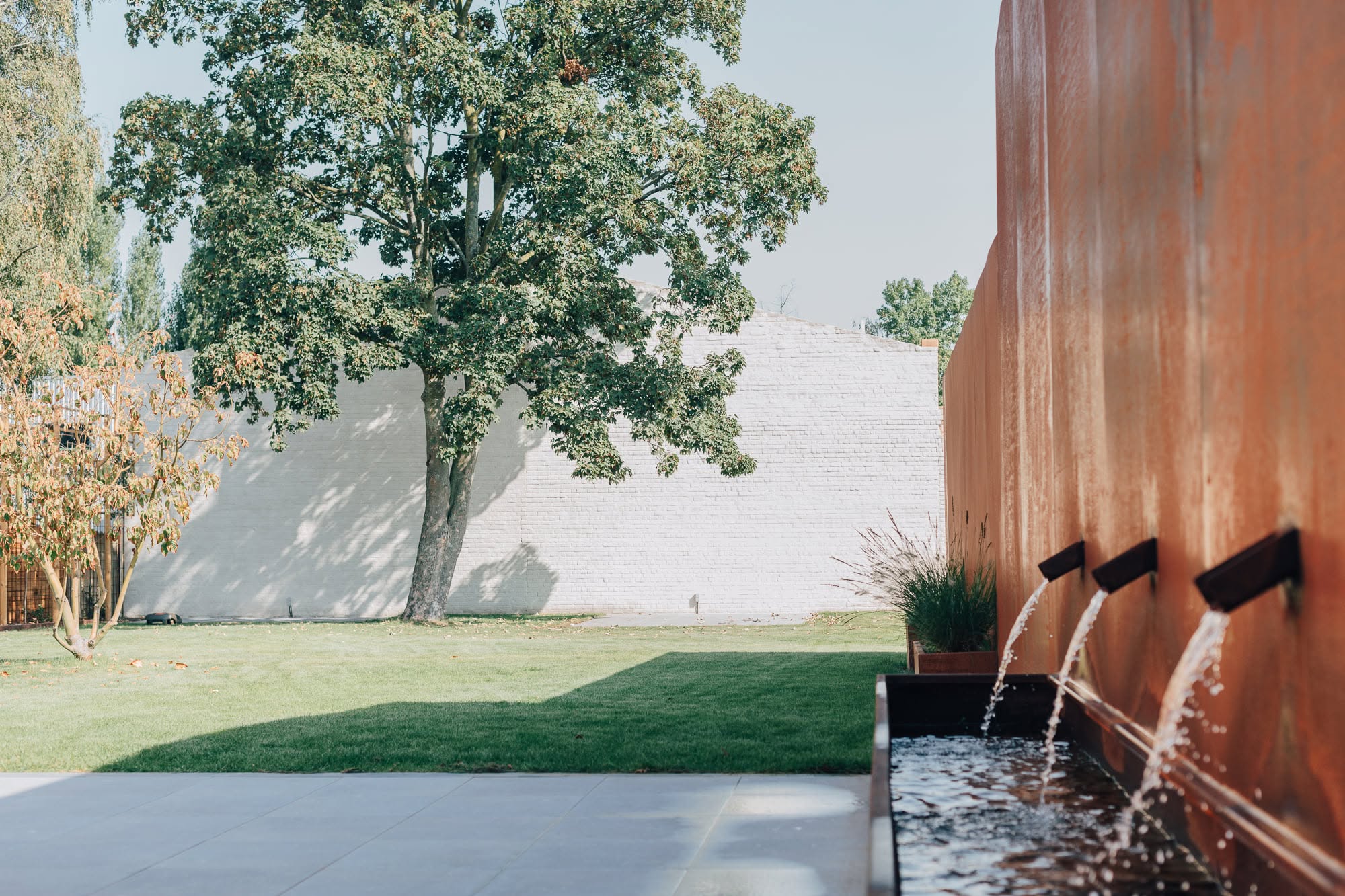 Waterwand in cortenstaal met drie uitlopen in een tuin