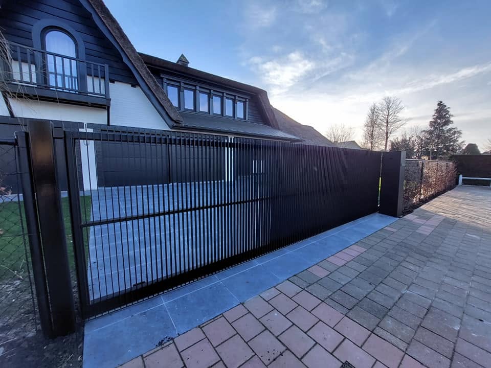 Zwart stalen hekwerk langs de oprit van een woning