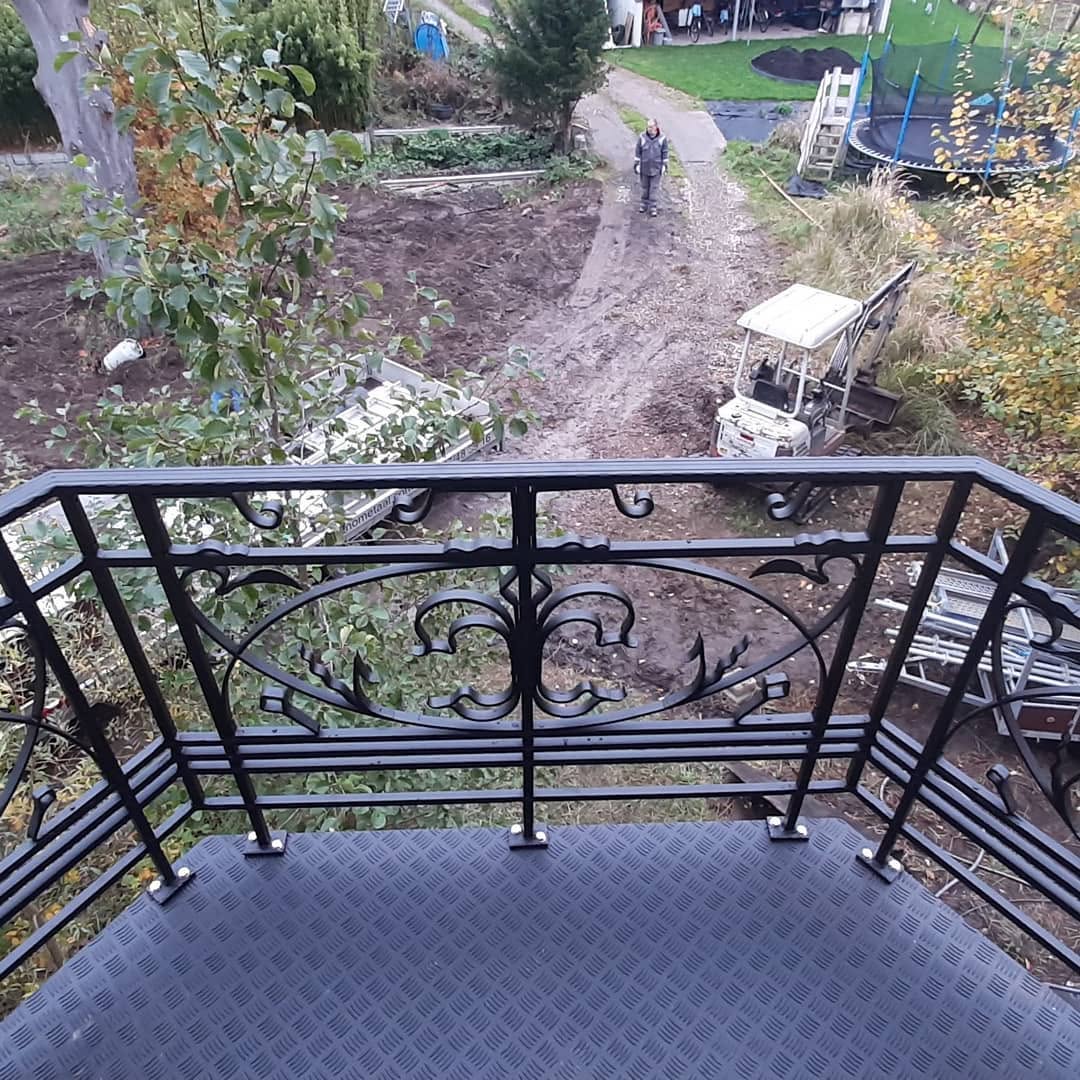 Smeedijzeren balustrade van een balkon met zicht op de tuin