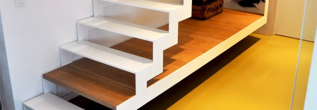 Witte stalen trap met houten treden boven een gele vloer